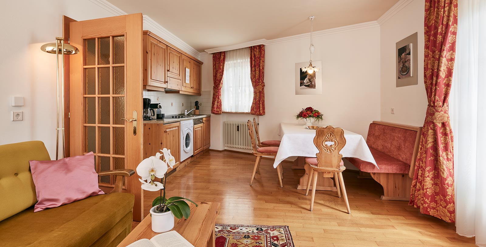 cucina e soggiorno di un appartamento nello Chalet Cristina con tipica panca in legno