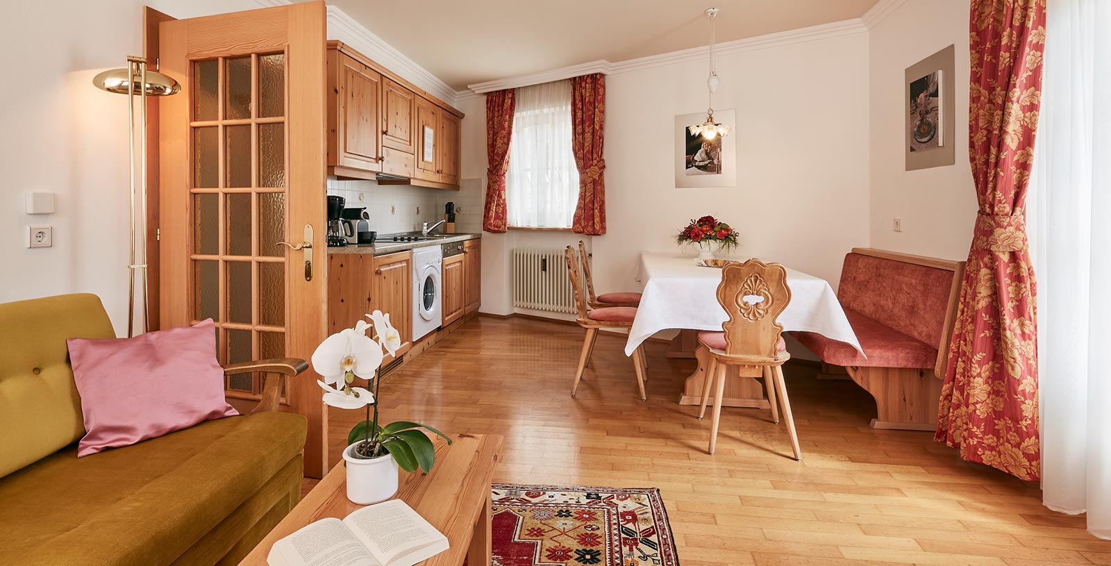 Kitchen-cum-living room of a holiday apartment of the Chalet Cristina with typical wooden bench